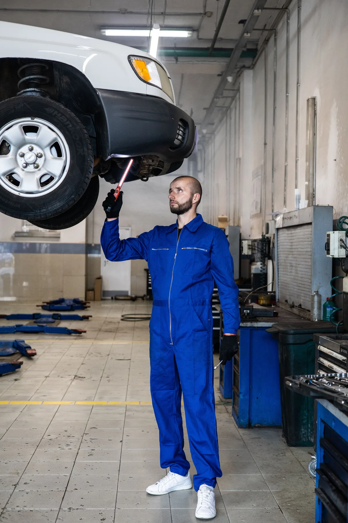 Stock photo of an automotive technician inspecting a raised vehicle